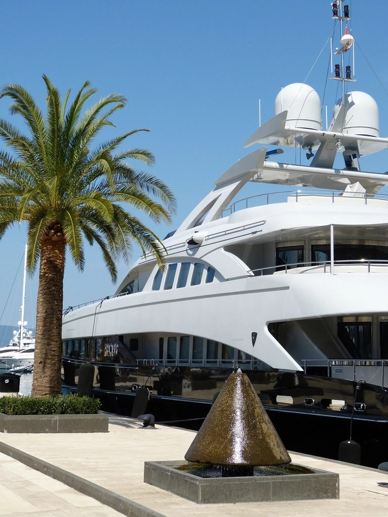 Superyacht moored beside palm trees in a marina
